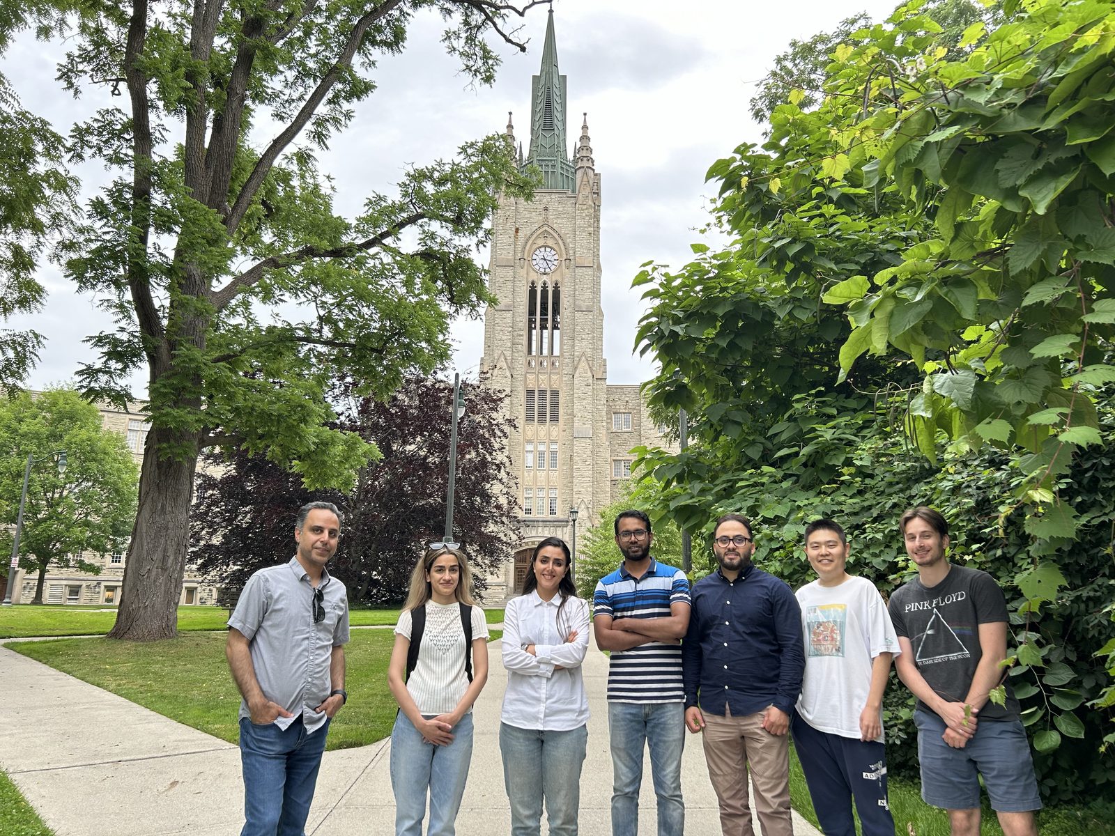 Lab members standing on a campus path with the Middlesex College tower behind them