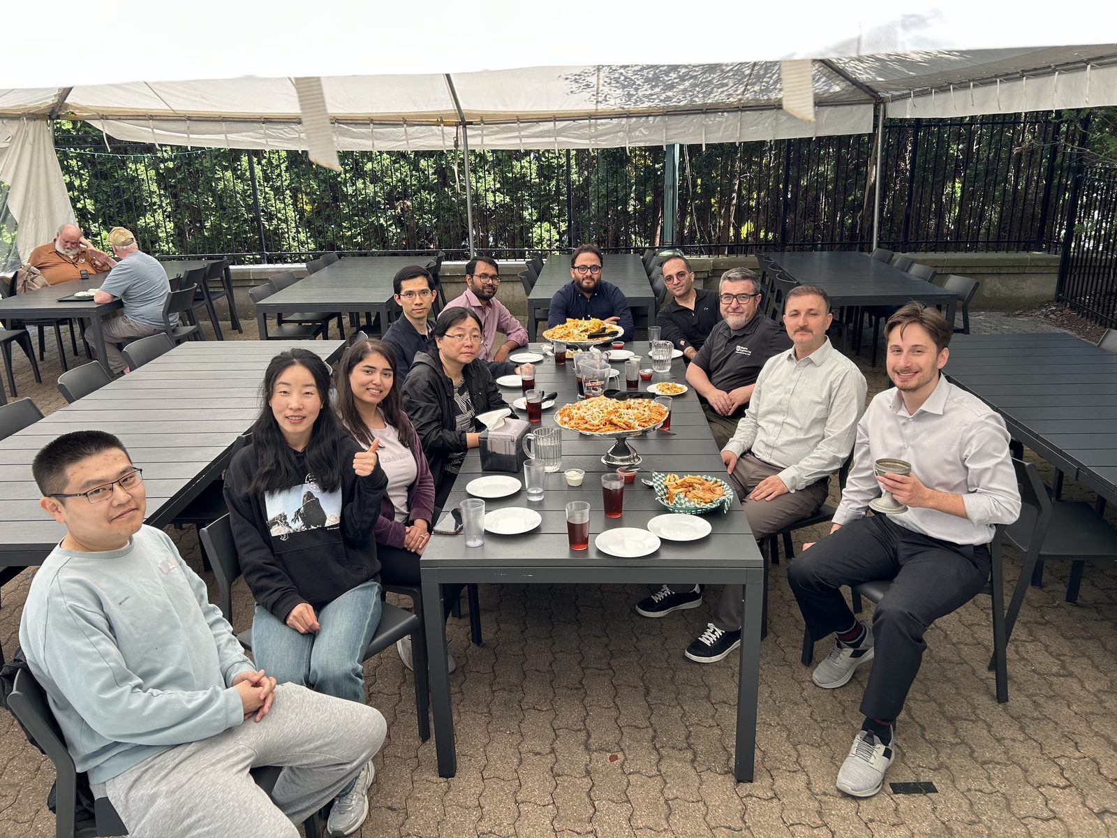 Lab members at a long patio table after Andrew Grgas-Svirac's MESc defence